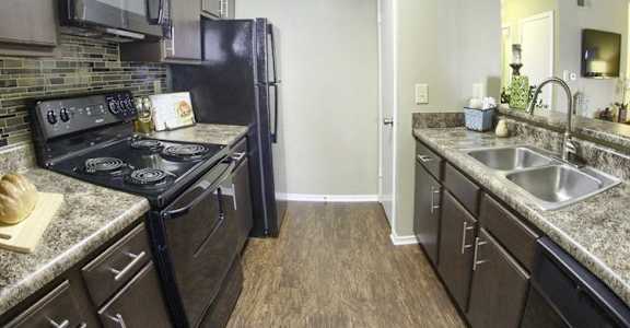 a kitchen with stainless steel appliances and granite counter tops and a black refrigerator