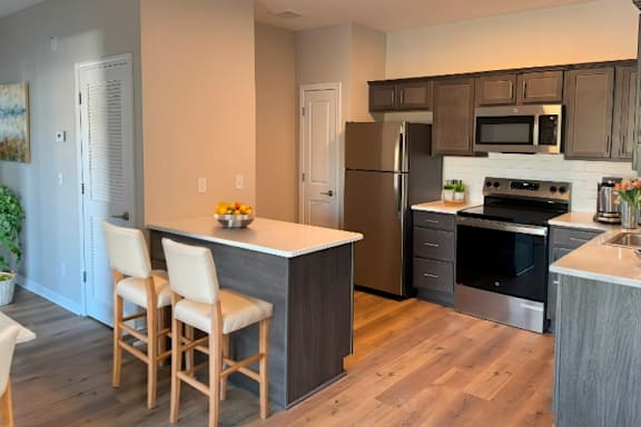 A kitchen with a white countertop and wooden chairs.