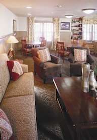 A living room with a brown couch and a painting of a horse on the wall.