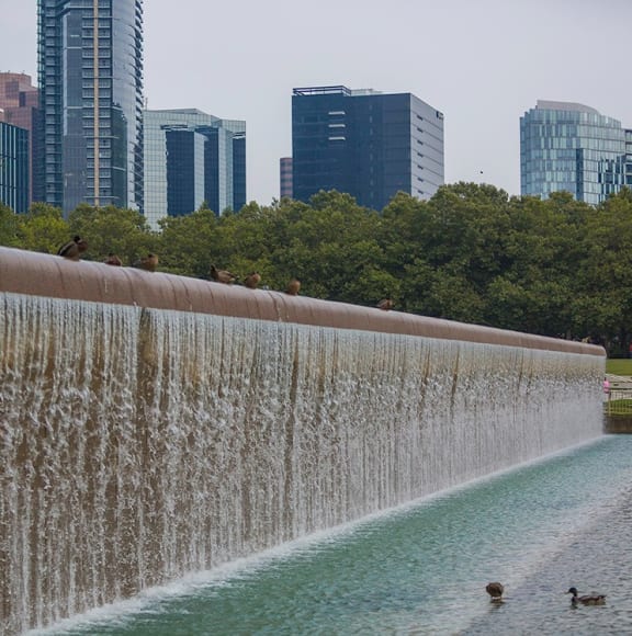 a cityscape with a large waterfall in the foreground and skyscrapers in the background