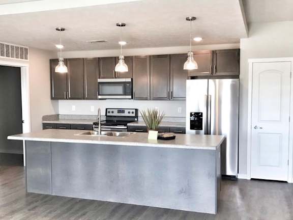 A modern kitchen with an island and dark cabinets.