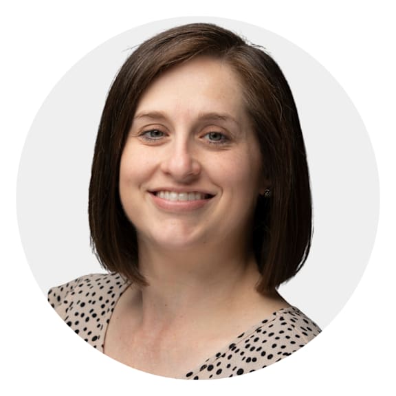 A woman with short brown hair and a polka dot top smiles at the camera.