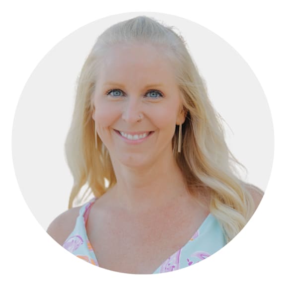 A woman with blonde hair and a floral top is smiling.