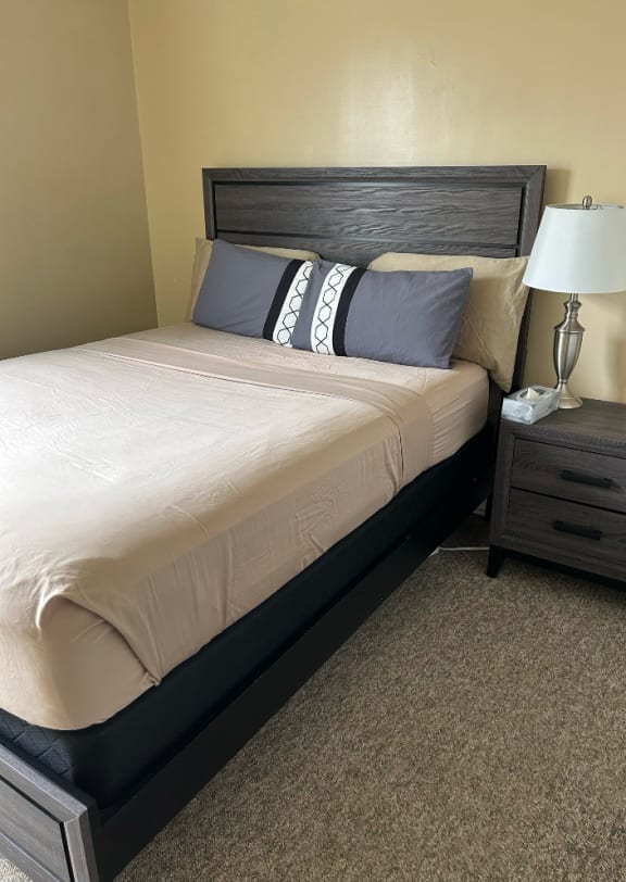 a bedroom with a bed and a nightstand with a lamp