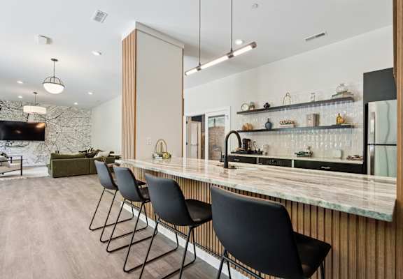 A kitchen with a marble countertop and black chairs.