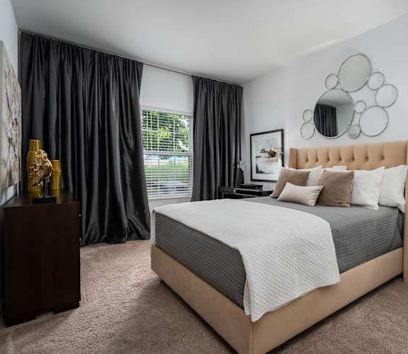 A bedroom with a large bed and a nightstand with a lamp.