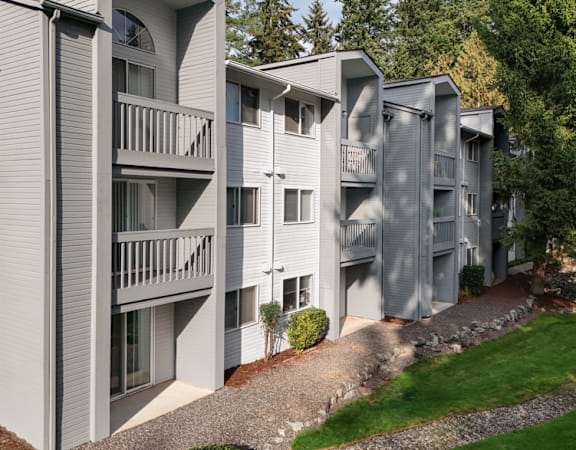 Apartment buildings with balconies and doors are surrounded by greenery.