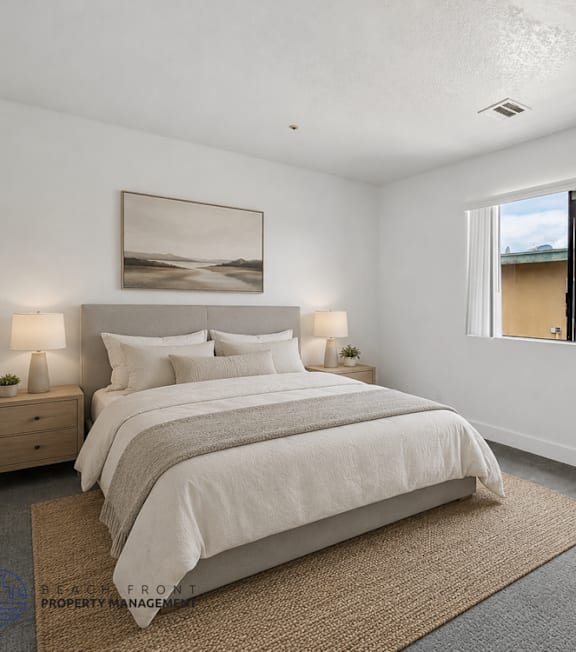 A well-lit bedroom with a large bed and a painting on the wall.