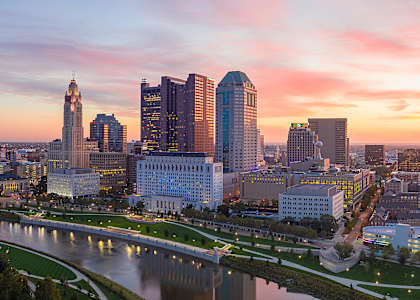 A city skyline at sunset with a river running through it.