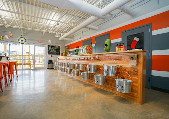 A long wooden table with metal buckets on it.