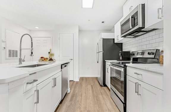 A kitchen with white cabinets and black appliances. at The Grayson Apartment Homes, North Carolina
