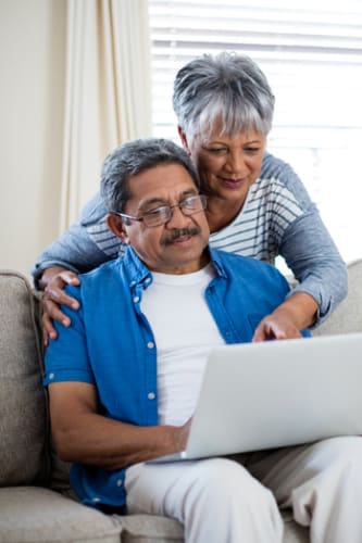 an older couple sitting on a couch looking at a laptop computer