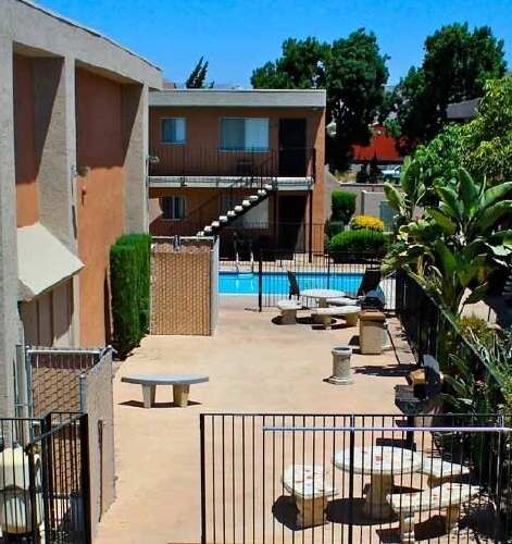 A sunny day at the poolside with a building in the background.