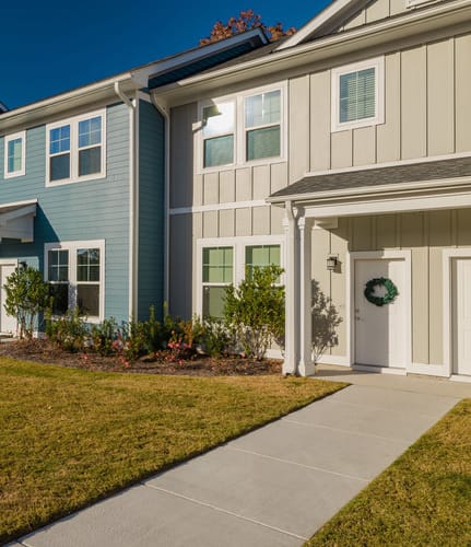 a row of townhomes with a grassy yard and a blue sky in the background