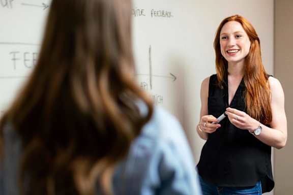 A woman is giving a presentation to a student in a classroom.