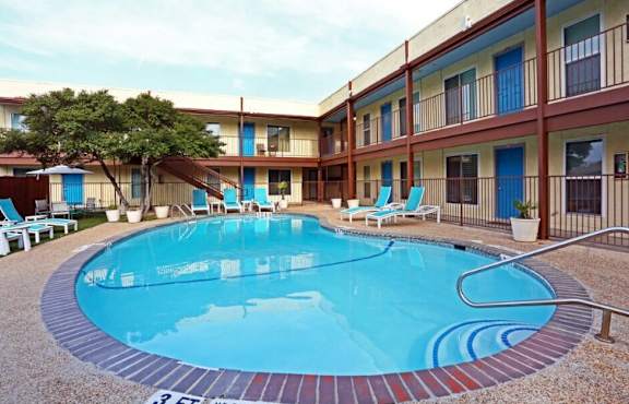 A small pool in front of a building with chairs around it.