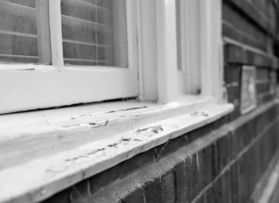A close up of a window sill with a brick wall.