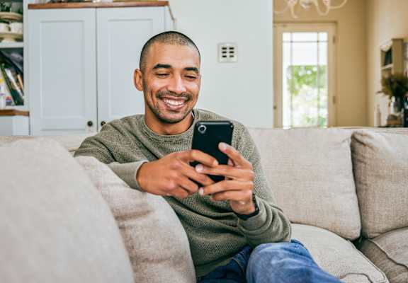 A man is sitting on a couch holding a phone.
