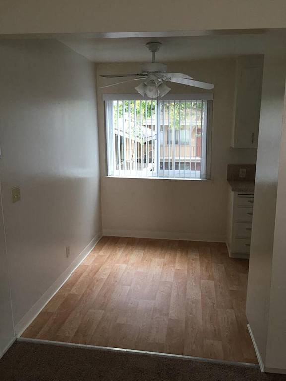 A room with wooden floors and a window with blinds.