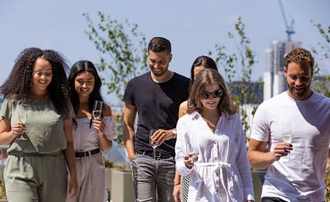 A group of people are walking together, each holding a glass of wine.