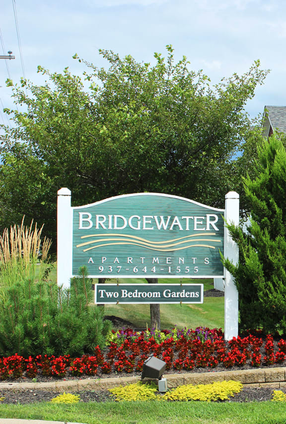 a sign for bridgewater apartments with flowers and trees in front of it