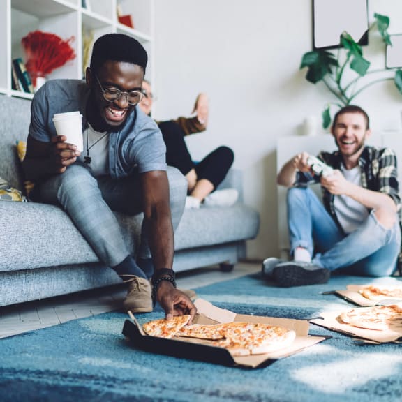 a group of people sitting on the floor eating pizza