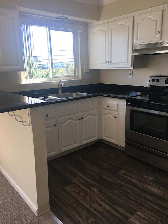 a kitchen with white cabinets and a sink and a window