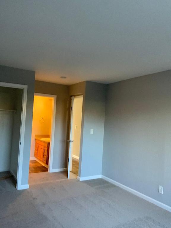 A room with a carpeted floor and a doorway leading to another room.