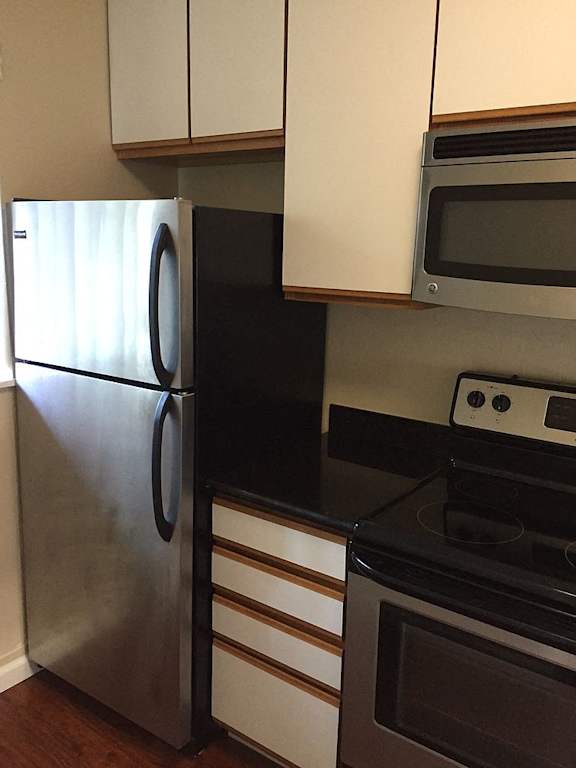 A kitchen with a black refrigerator and white cabinets.