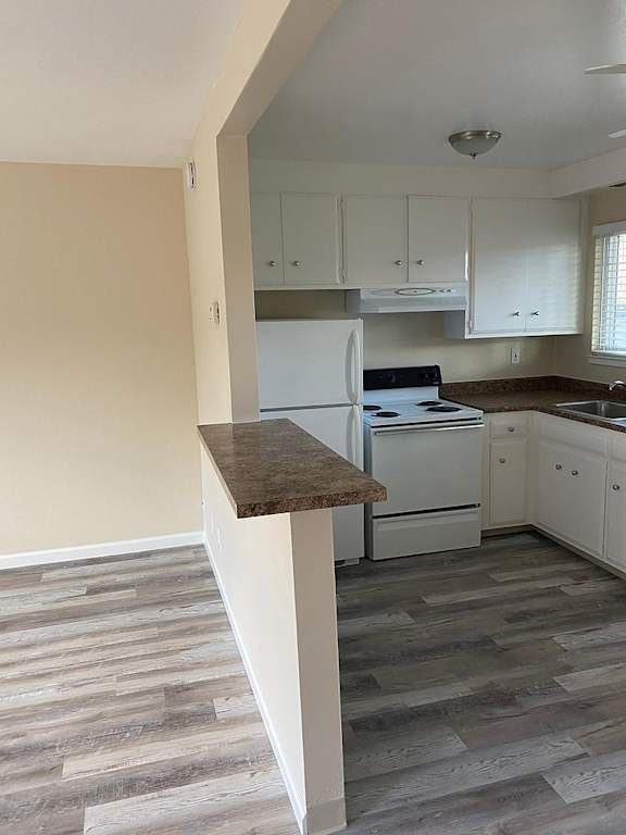 A kitchen with a white fridge and cabinets.