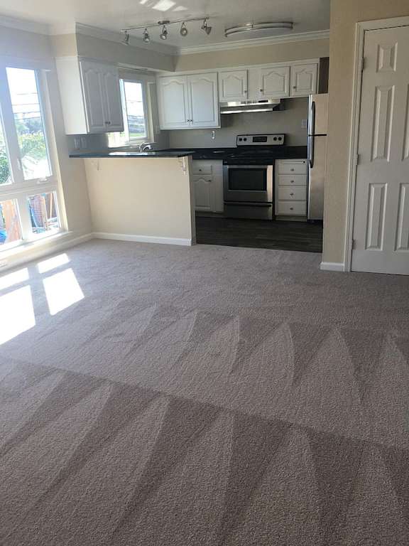 an empty kitchen and living room with a carpeted floor