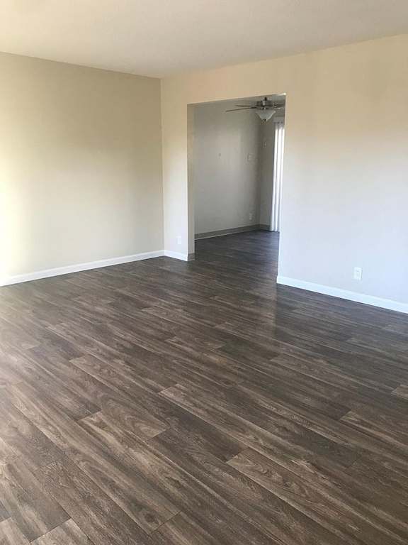 A room with wood flooring and a doorway leading to another room.
