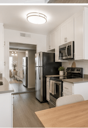 A modern kitchen with white cabinets and a wooden table.