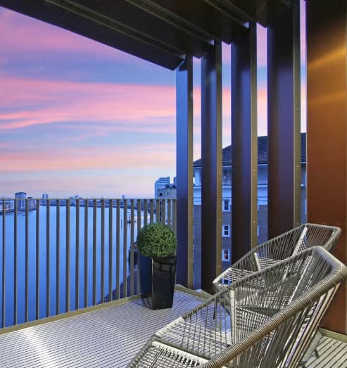 a balcony with a view of the water at sunset