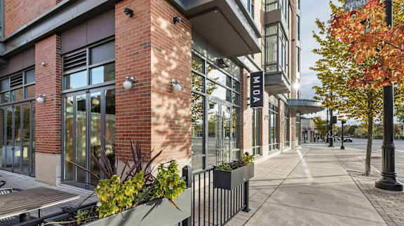 A street view of a building with the name  at Trio Newton Apartments, Newton, MA, 02460