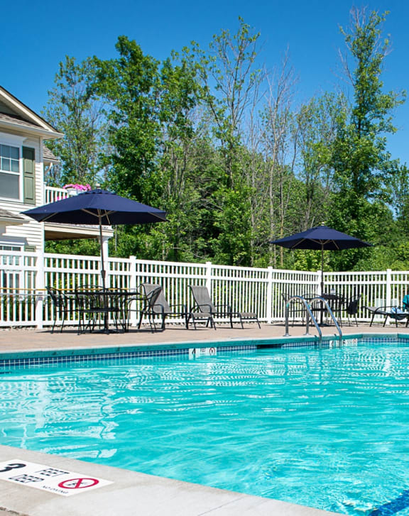 our resort style swimming pool is surrounded by chairs and a white fence