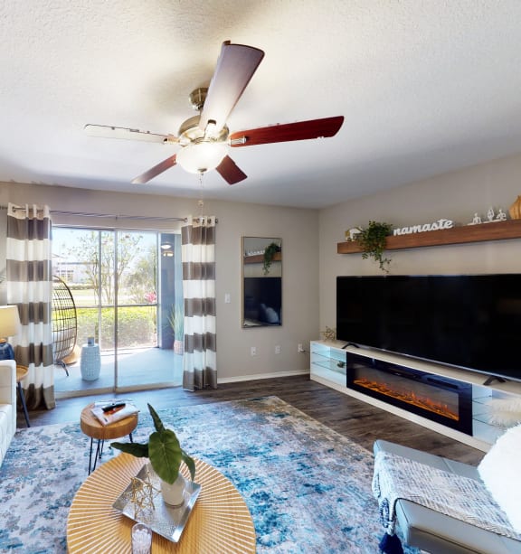 a living room with a couch and a ceiling fan and a tv