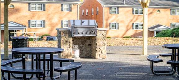 A patio with tables and a fireplace in front of a brick building.