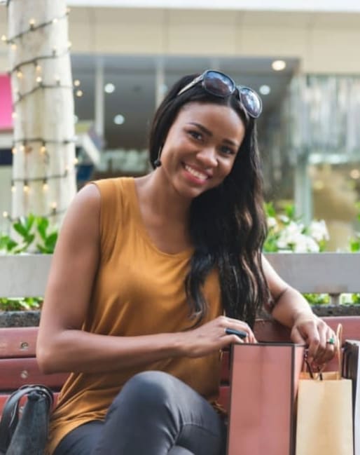 A woman is sitting on a bench with shopping bags.