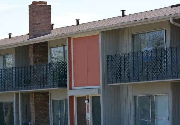 A building with a red door and a balcony with a black railing.