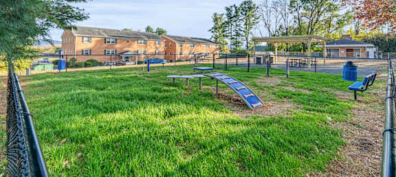 A park with a playground and a building in the background.