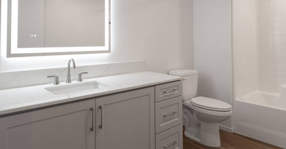 A white bathroom with a sink, toilet, and mirror.