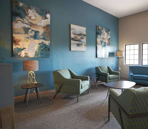 A living room with blue walls and green chairs.