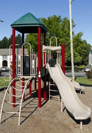 A playground with a red and white slide and a green roofed structure.