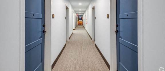 a long hallway with blue doors and white walls