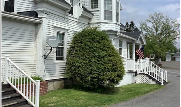 A white house with a black roof and a tower.