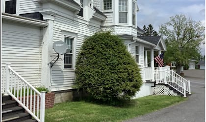 A white house with a black roof and a tower.