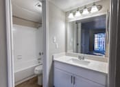 Thumbnail 3 of 5 - A white bathroom with a sink, mirror, and bathtub.