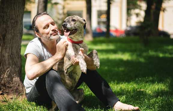 A man is sitting on the grass with his dog.