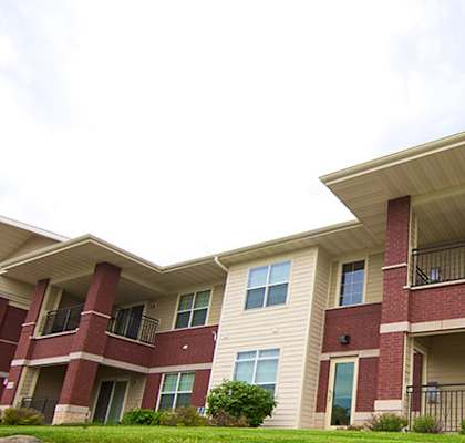Apartment building with red brick and beige siding.